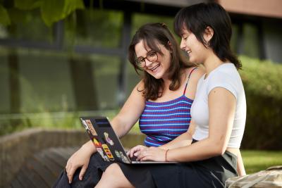 Two female students sitting together and using a laptop